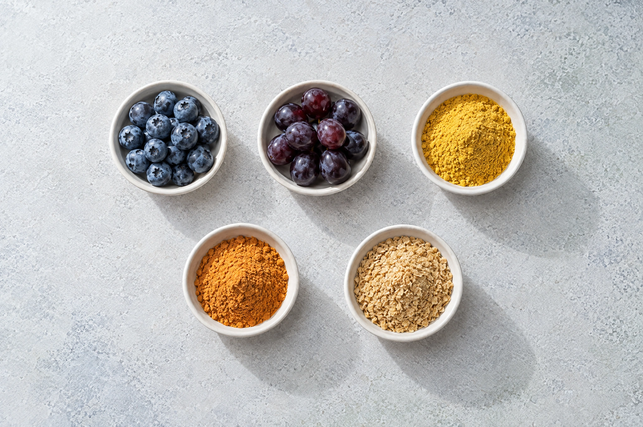 Five bowls of active ingredients on a light stone surface